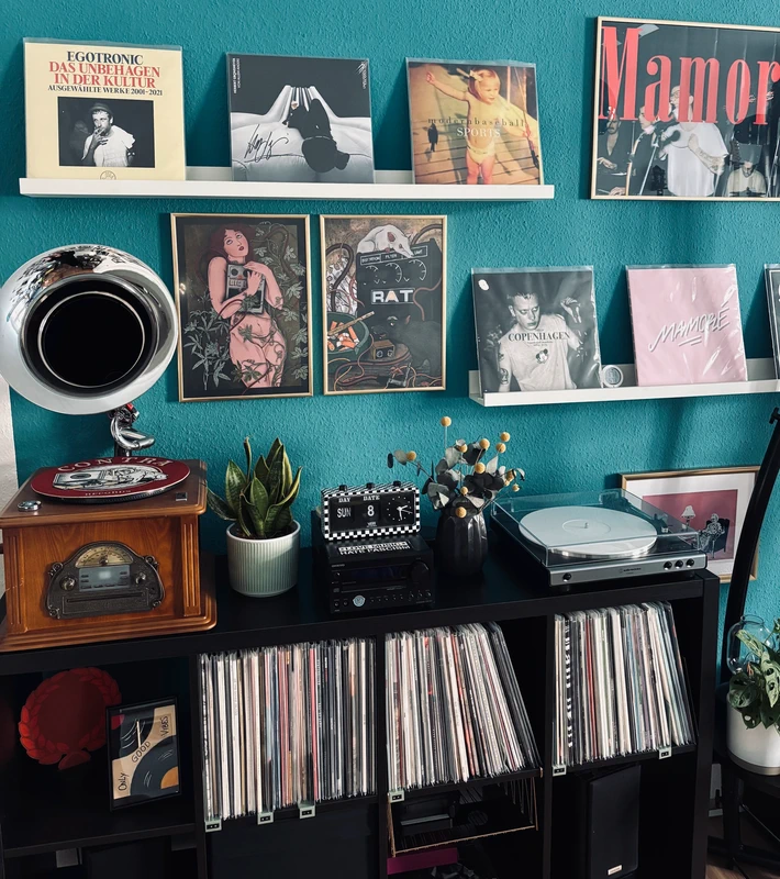 Ästhetisches Vinyl-Setup mit Plattenspieler und Schallplatten an türkisfarbener Wand im Retro-Stil